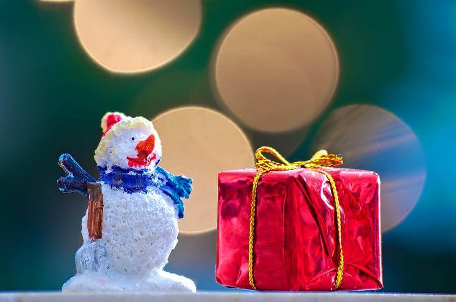 Snowman figure beside a red Christmas gift box